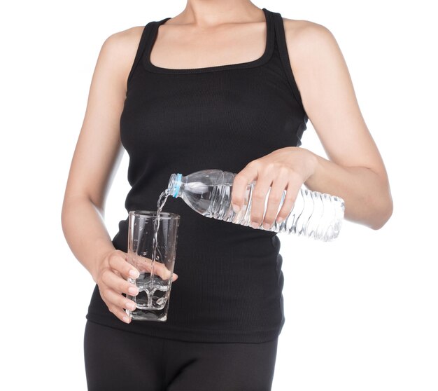 gezonde vrouw met een fles water Het gieten van water in een glas geïsoleerd op een witte achtergrond.