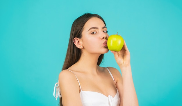 Gezonde vrouw met groene appel. Kus blazen. Mooie jonge vrouw die een appel eet. Gezonde levensstijl. Gelukkige vrouw kus appel op blauwe achtergrond.