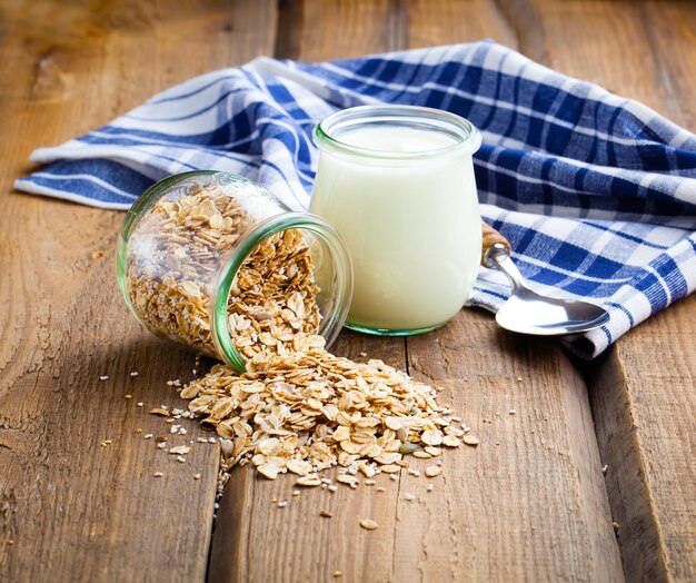 Gezonde yoghurt met havervlokken in een glazen pot op een houten achtergrond