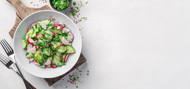 Gezonde zomersalade met verse kruiden van radijskomkommer op een lichtgrijze ondergrond