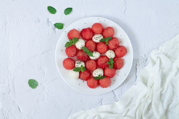 Gezonde zomersalade van watermeloen, mozzarella, muntblaadjes en chiazaadjes bovenaanzicht