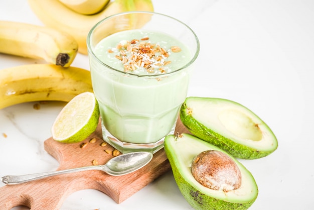 Gezonde zomerse drank, avocado en banaan smoothie met limoen, muesli en kokosmelk