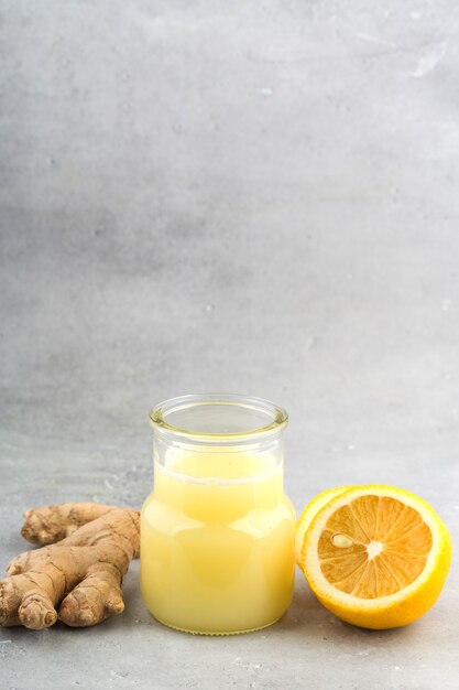 Gezondheid en dieet inhoud. Natuurlijke ondersteuning van het immuunsysteem - gember- en citroendrank. Lichtgrijze achtergrond, verticaal formaat.