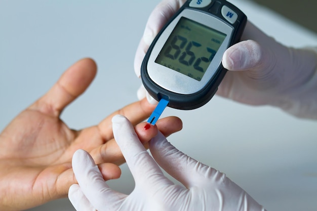 Foto gezondheid en geneeskunde conceptbloedglucometer de bloedsuikerwaarde wordt op een vinger gemeten