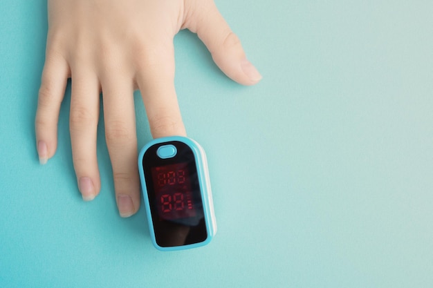 Gezondheid en geneeskunde Diagnose van aandoeningen van de luchtwegen Vrouwelijke vinger in een pulsoximeter op een blauwe achtergrond