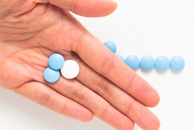 Gezondheid en medicijnconcept blauwe en witte pillendrug of tabletten in vrouwenhand met exemplaarruimte