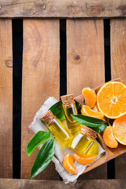 Gezondheid en schoonheid stilleven concept biologische essentiële mandarijn mandarijn clementine olie in een kleine glazen pot en oranje fruit op een rustieke houten tafelblad weergave kopie ruimte achtergrond