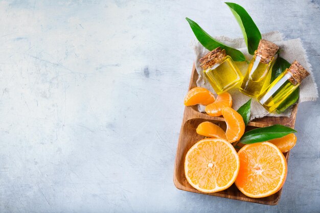 Gezondheid en schoonheid stilleven concept Biologische essentiële mandarijn mandarijn clementine olie in een kleine glazen pot met groene bladeren en oranje fruit Kopieer ruimte achtergrond bovenaanzicht plat lag overhead