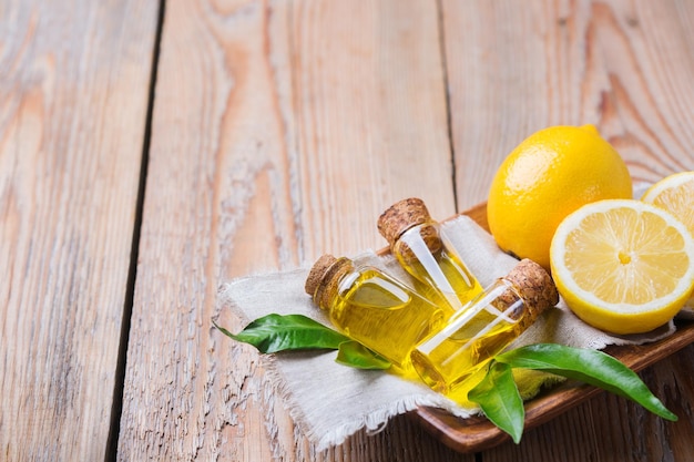 Gezondheid en schoonheid stilleven concept Biologische etherische citroenolie in een kleine glazen pot met groene bladeren en geel fruit op een rustieke houten tafel Kopieer ruimte achtergrond