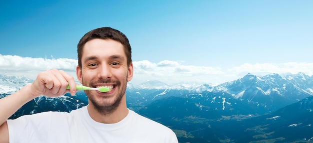 Foto gezondheid en schoonheidsconcept - glimlachende jonge mens met tandenborstel