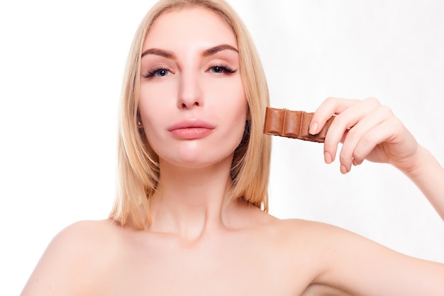 Gezondheid, mensen, voedsel en schoonheidsconcept - Mooie glimlachende tiener die chocolade eet. Portret van mooie vrouw met chocoladereep.