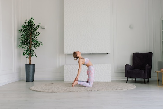 Gezondheidsconcept. Jonge mooie vrouw doet yoga-oefening in de moderne kamer