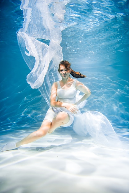 Foto gezondheidsconcept voor vrouwen. meisje onderwater in het wit. lichtheid, frisheid en gezondheid