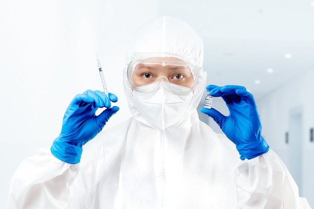 Gezondheidswerker vrouw met een beschermend pak en handschoenen met covid 19 vaccins in het ziekenhuis