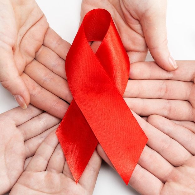 Gezondheidszorg en geneeskunde concept. aids-bewustzijn. De handen van veel mensen houden een groot rood bewustzijnslint vast. Internationale aidsdag.