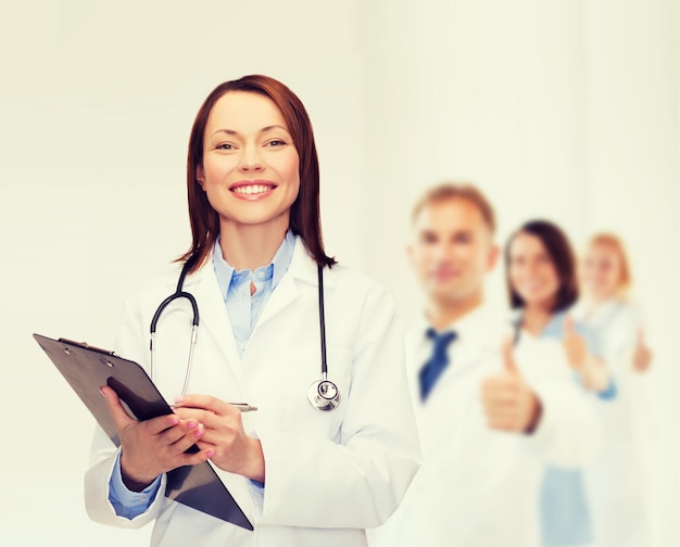 gezondheidszorg en geneeskundeconcept - glimlachende vrouwelijke arts met klembord en stethoscoop