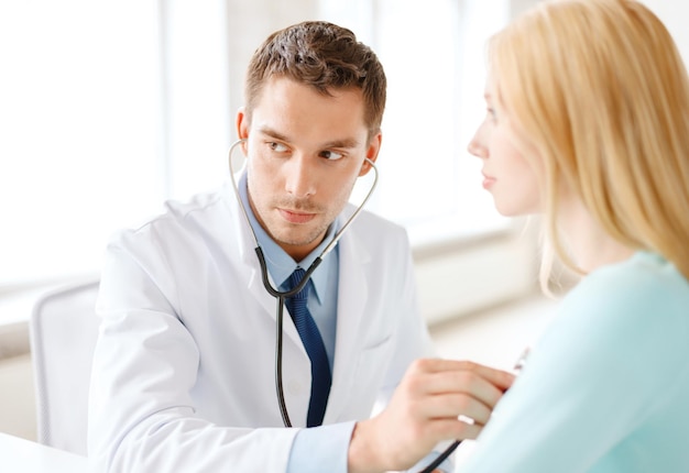 gezondheidszorg en medisch concept - geconcentreerde mannelijke arts met stethoscoop luisteren naar de patiënt in het ziekenhuis