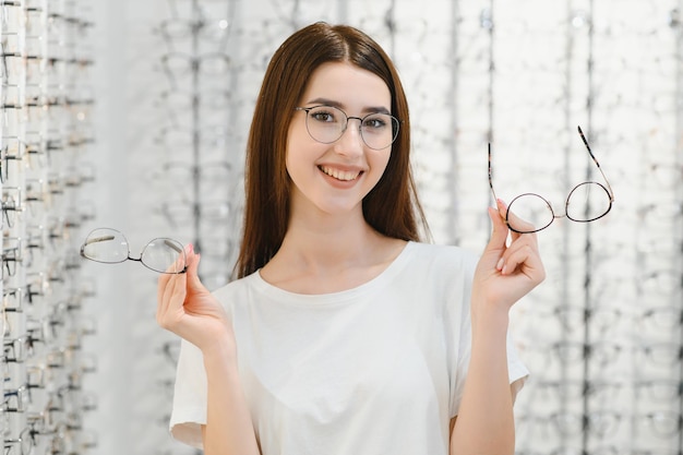 Gezondheidszorg gezichtsvermogen en visie concept gelukkige vrouw die een bril kiest bij optiekwinkel Jong mooi meisje in een optiekwinkel die een nieuwe bril probeert