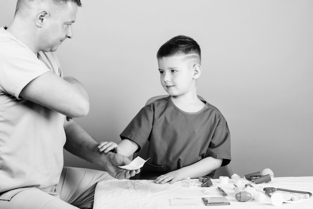 Gezondheidszorg Medisch onderzoek Jongen schattig kind en zijn vader arts Ziekenhuis werknemer Medische hulp Medische verzekering EHBO geneeskunde concept Kid kleine dokter zitten tafel medische hulpmiddelen