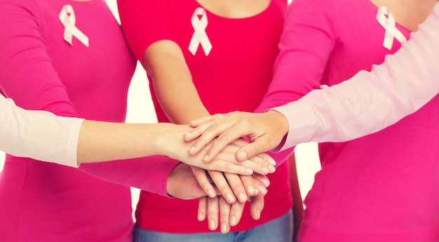 gezondheidszorg, mensen, gebaar en geneeskunde concept - close-up van vrouwen in lege shirts met roze borstkanker bewustzijn linten handen bovenop witte achtergrond