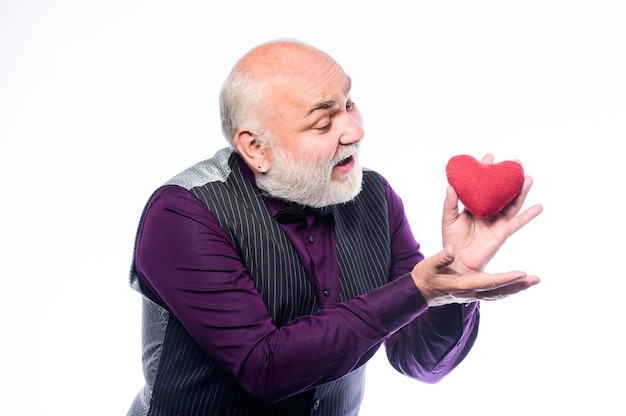 Gezondheidszorg. senior kale hoofd bebaarde man houdt rood hart vast. hartaanval voorkomen. hartprobleem en gezondheidszorg. volwassen man met valentijnsdag hart. verliefd worden. hartslagdiagnostiek en behandeling.