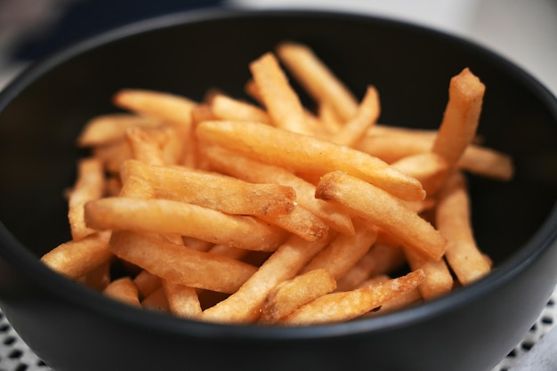 Foto gezouten friet in een witte schaal op een houten dienblad