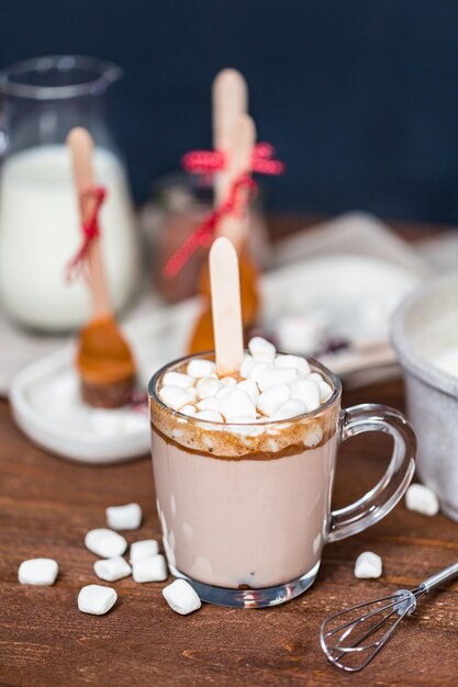 Gezouten karamel warme cacao lepel in glazen beker gegarneerd met marshmallows.