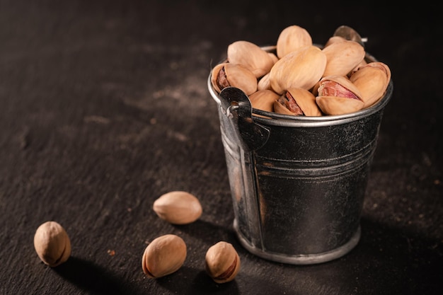 Gezouten pistachenoten verspreid over de tafel van een gevallen emmer