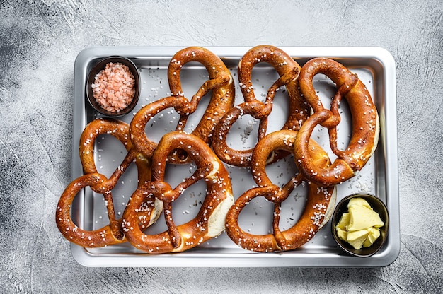 Gezouten pretzels met zeezout op een keukenbakselpan. Witte achtergrond. Bovenaanzicht.