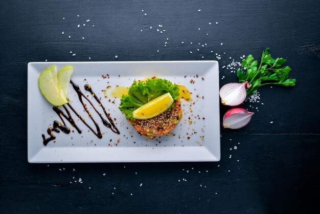 Gezouten zalm en verse groenten met balsamicosaus in een bord Op een houten ondergrond Bovenaanzicht Vrije ruimte