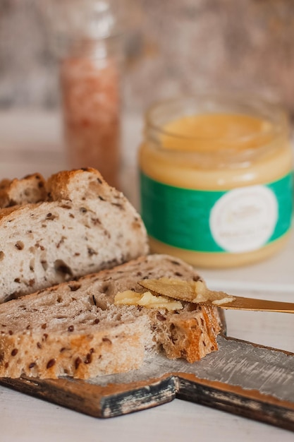 Ghee boter in glazen pot en gesneden brood op tafel Gezond eten ontbijt