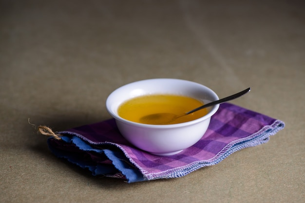 Ghee butter from India in white dinnerware container on wooden table.