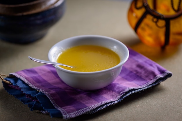 Ghee butter from India in white dinnerware container on wooden table.