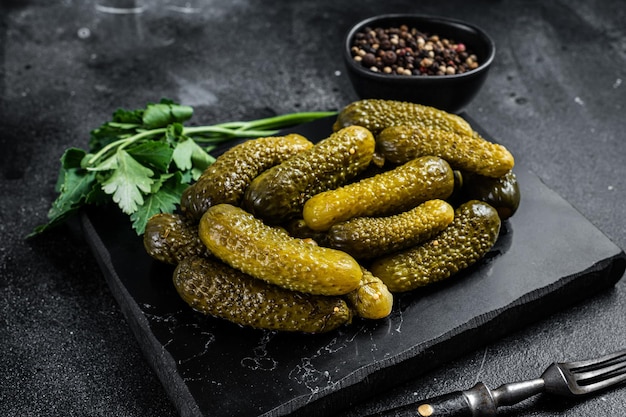 Gherkin Pickled cucumbers with garlic and spices. Black background. Top view.