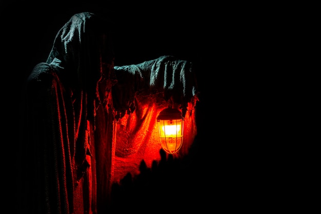 The ghost holds a burning lantern on a dark background horror