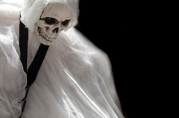 Ghost with human skull white cloth in darkness on grunge halloween background