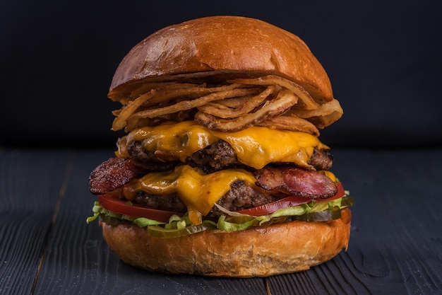 Giant beef burger with frankfurters on a black background