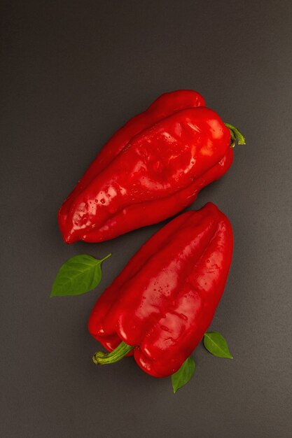 Giant red bell pepper isolated on black stone background. Sweet vegetable, new harvest, fresh ingredient for healthy food. Dark culinary wallpaper, top view