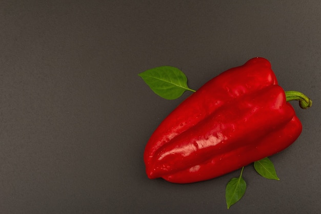 Giant red bell pepper isolated on black stone background. Sweet vegetable, new harvest, fresh ingredient for healthy food. Dark culinary wallpaper, top view