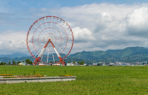 Giant red and white Ferris wheel with mountains