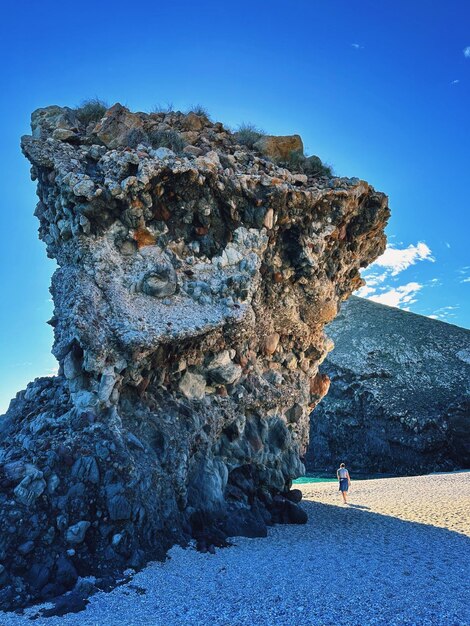 Giant rock formation at the playa de los muertos with a man walking alongside