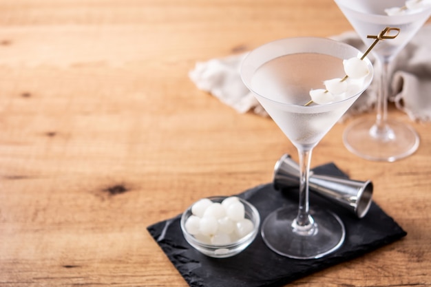 Gibson martini cocktail with onions on wooden table