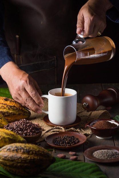 Giet een heerlijke warme chocolademelk cacaodrank in een mok met zwarte tafel low key zwarte achtergrond