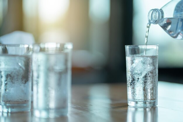 Giet het water in een glas met ijs.