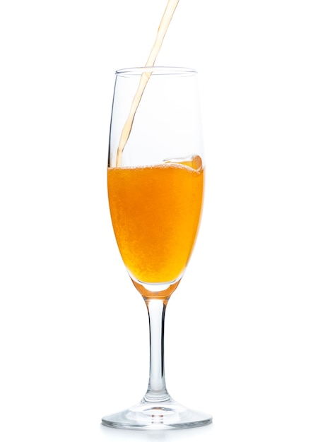 Giet oranje frisdrank in champagne glas geïsoleerd op een witte achtergrond, zomer drank concept