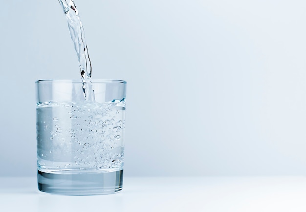 Giet water in een drinkglas