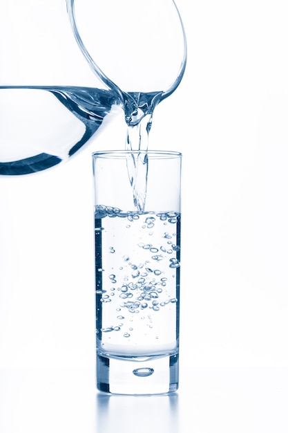 Giet water uit een kan in een glas