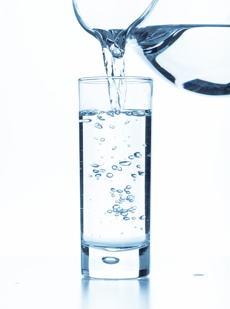 Giet water uit een kruik in een glas