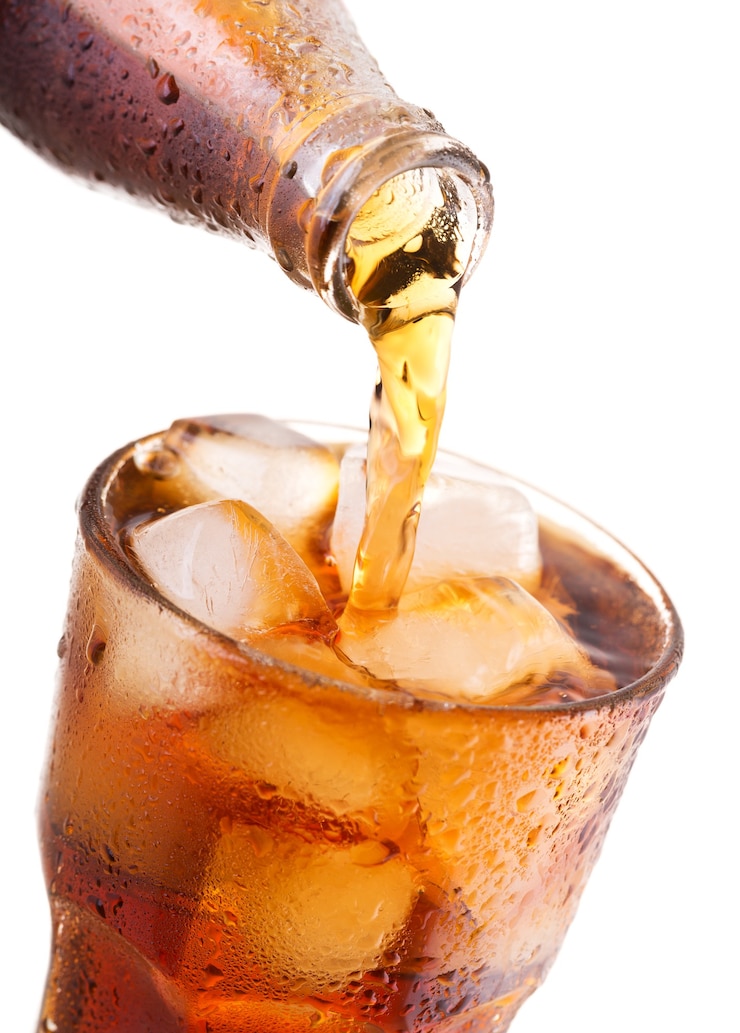 Foto gieten cola in glas met ijs uit fles geïsoleerd op een witte achtergrond