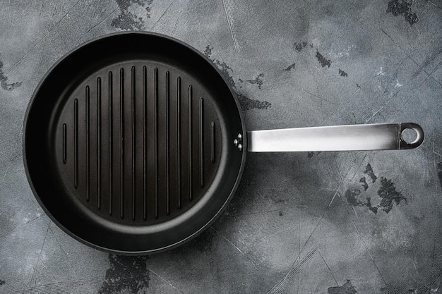 Foto gietijzeren grillpan set met kopieerruimte voor tekst of eten met kopieerruimte voor tekst of eten, bovenaanzicht plat lag, op grijze stenen tafelachtergrond